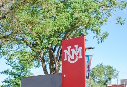 University of New Mexico red welcome sign against green trees
